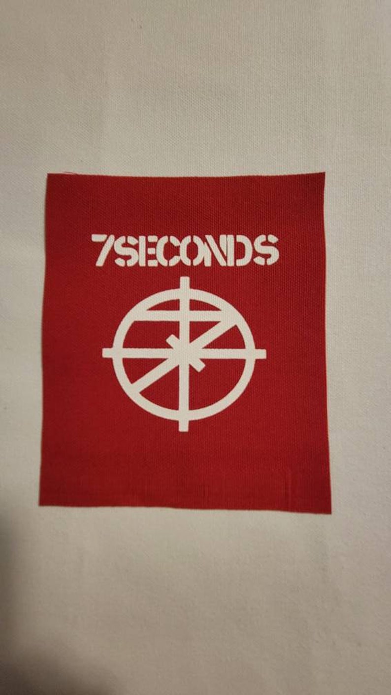 May include: Red fabric patch with white text that reads "7 SECONDS" and a white circle with a cross inside.