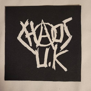 Op de afbeelding: Zwarte patch met witte tekst die "Chaos U.K." in een gestileerd lettertype leest.