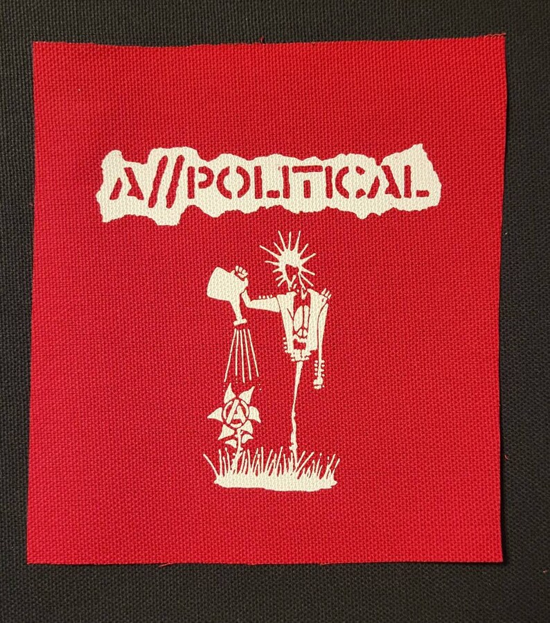 May include: A red fabric patch with white text that reads "A//POLITICAL". A white silhouette of a figure holding a watering can and watering a flower with an anarchy symbol in the center is below the text.