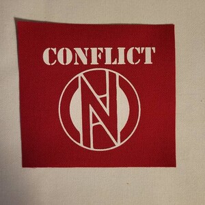 May include: Red fabric patch with white text that reads "CONFLICT" and a white circle with a stylized "N" inside.