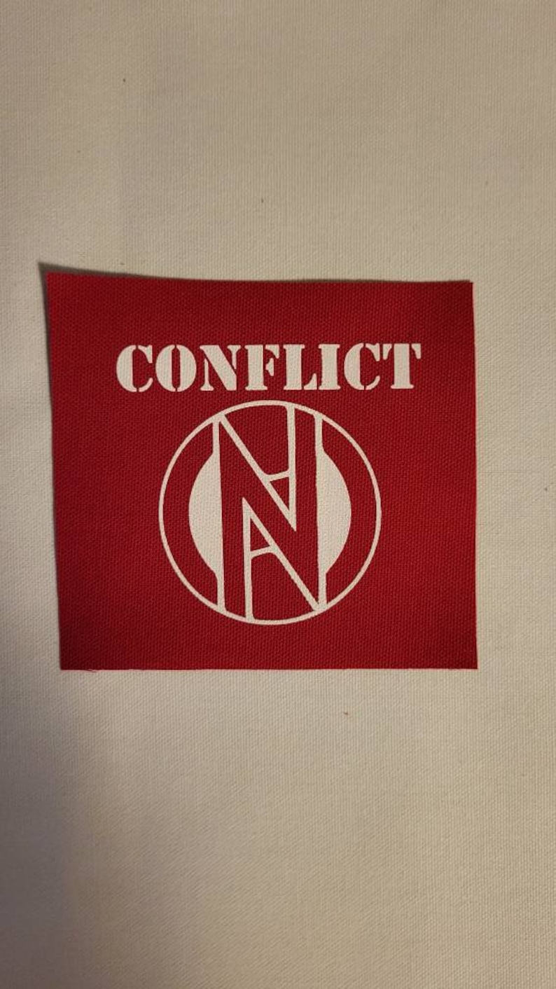 May include: Red fabric patch with white text that reads "CONFLICT" and a white circle with a stylized "N" inside.