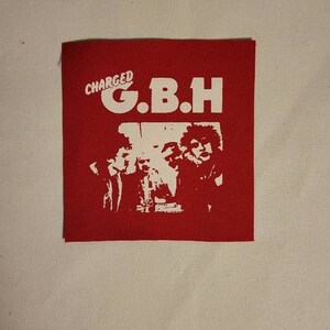 K&ouml;nnte beinhalten: Roter Stoff-Patch mit wei&szlig;em Text "CHARGED G.B.H." und einem Schwarzwei&szlig;bild einer Band.