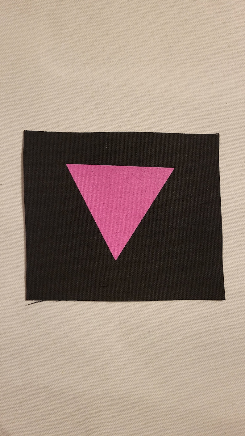 May include: A pink triangle on a black fabric patch.