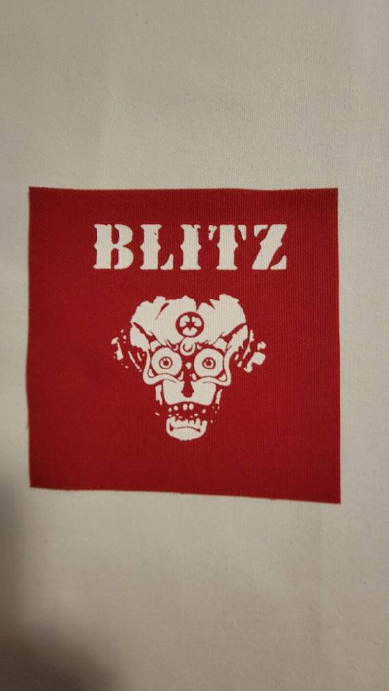 May include: Red fabric patch with white text that reads "BLITZ" and a white skull with a third eye in the center.