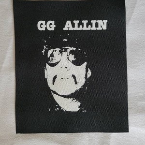 Könnte beinhalten: Schwarz-weiß-Patch mit dem Text "GG ALLIN" in weißen Buchstaben. Der Patch zeigt ein Schwarz-Weiß-Bild einer Person mit Sonnenbrille.