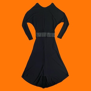 May include: A black dress with long sleeves and a wide, textured belt. The dress has a flowing skirt and a scoop neckline. The dress is displayed against an orange background.
