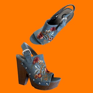 Può includere: Due sandali slingback in denim con ricami floreali. I sandali hanno tacchi a blocco in legno, fibbie color argento e punta aperta. I tacchi misurano circa 10 cm.