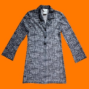 Könnte beinhalten: Eine schwarze und weiße langärmelige Jacke mit einem abstrakten geometrischen Muster. Die Jacke hat einen Kragen und einen Knopfverschluss.