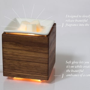May include: A wooden diffuser with a white ceramic dish on top. The dish contains wax melts that are melting and releasing a fragrance into the air. The diffuser has a soft glow that lets you know it's on.