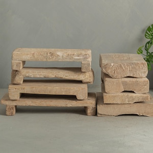 May include: Several rustic, light-colored wooden risers of varying heights are arranged on a gray surface. The risers have a natural, weathered appearance, with visible wood grain and a rectangular shape. Some are stacked, suggesting a display or decorative purpose.