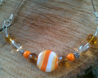May include: A necklace with orange and brown glass beads and a large orange and white striped bead in the center.