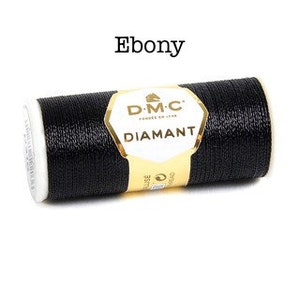 May include: A spool of black DMC Diamant embroidery thread. The spool is labeled "D.M.C. Diamant" and "Ebony".
