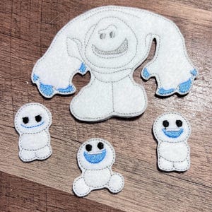 Puede incluir: Apliques de fieltro blanco con tem&aacute;tica de mu&ntilde;eco de nieve, con costuras grises y detalles azules. El conjunto incluye un mu&ntilde;eco de nieve grande y tres mu&ntilde;ecos de nieve m&aacute;s peque&ntilde;os, todos con caras sonrientes. Para manualidades y decoraci&oacute;n.