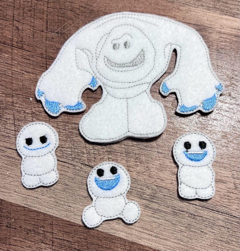 Puede incluir: Apliques de fieltro blanco con tem&aacute;tica de mu&ntilde;eco de nieve, con costuras grises y detalles azules. El conjunto incluye un mu&ntilde;eco de nieve grande y tres mu&ntilde;ecos de nieve m&aacute;s peque&ntilde;os, todos con caras sonrientes. Para manualidades y decoraci&oacute;n.