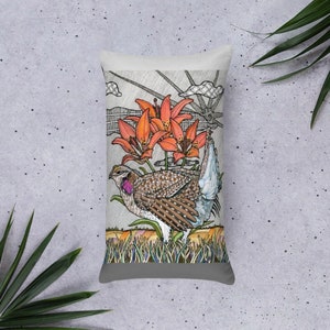 May include: A decorative cushion featuring a hand-drawn illustration of a bird with a long tail and orange lilies. The bird is brown and white with a pink breast. The background is a light grey with a checkered pattern.