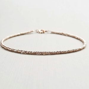 May include: A delicate gold-toned bracelet made of tiny beads.