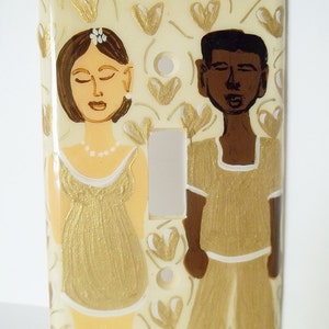 Könnte beinhalten: Ein Lichtschalter-Abdeckung mit einem gemalten Design eines Paares. Die Frau trägt ein goldenes Kleid und der Mann trägt ein goldenes Hemd und eine Hose. Der Hintergrund ist cremefarben mit goldenen Herzen.