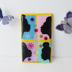 Puede incluir: Una cubierta decorativa para interruptor de luz con borde amarillo, que presenta cuatro paneles con perfiles de siluetas negras sobre fondos azules, rosas y amarillos. Dos mariposas moradas están colocadas a cada lado.