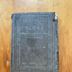 May include: A worn, dark brown book with the title "An Evening at Scott" by Sherwin Cody and the text "The Nutshell Library" on the cover.