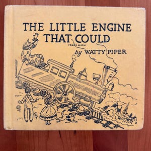 May include: A vintage children's book titled "The Little Engine That Could" by Watty Piper. The cover is a light yellow with black illustrations of a train, characters, and text. The book has a classic, nostalgic feel.
