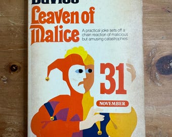 Könnte beinhalten: Vintage Taschenbuchcover für "Leaven of Malice" von Robertson Davies. Das Cover zeigt eine Narrenillustration in Orange, Gelb und Blau, mit der Zahl "31" und dem Wort "November". Das Pinguin-Logo befindet sich in der oberen rechten Ecke.