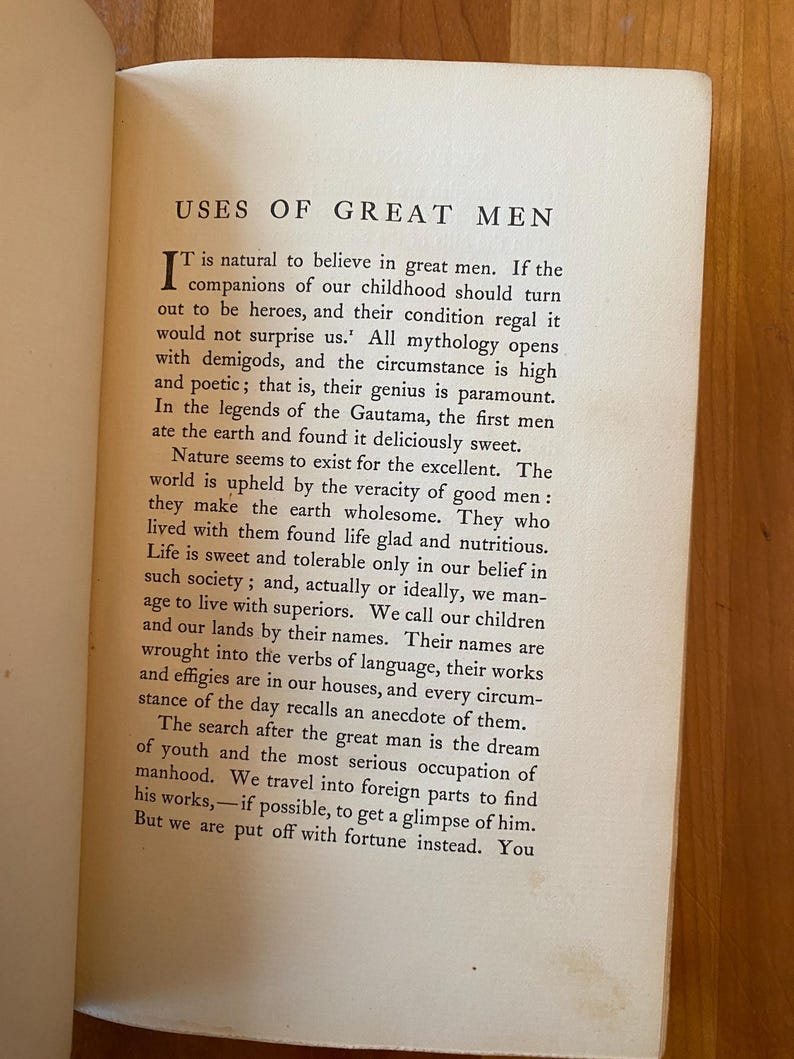 Pu&ograve; includere: Una pagina di un libro vintage intitolato "Uses of Great Men". Il testo discute l'importanza degli uomini grandi nella societ&agrave; e come le loro vite e le loro opere ci ispirano.