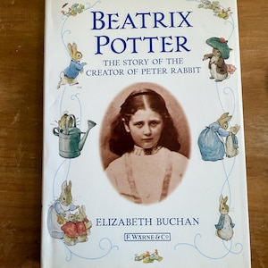 Może przedstawiać: Twarda oprawa książki zatytułowana "Beatrix Potter" z ilustracjami królików i portretem młodej dziewczyny. Na okładce widnieje napis "The Story of the Creator of Peter Rabbit" i "Elizabeth Buchan", wydane przez F. Warne & Co.