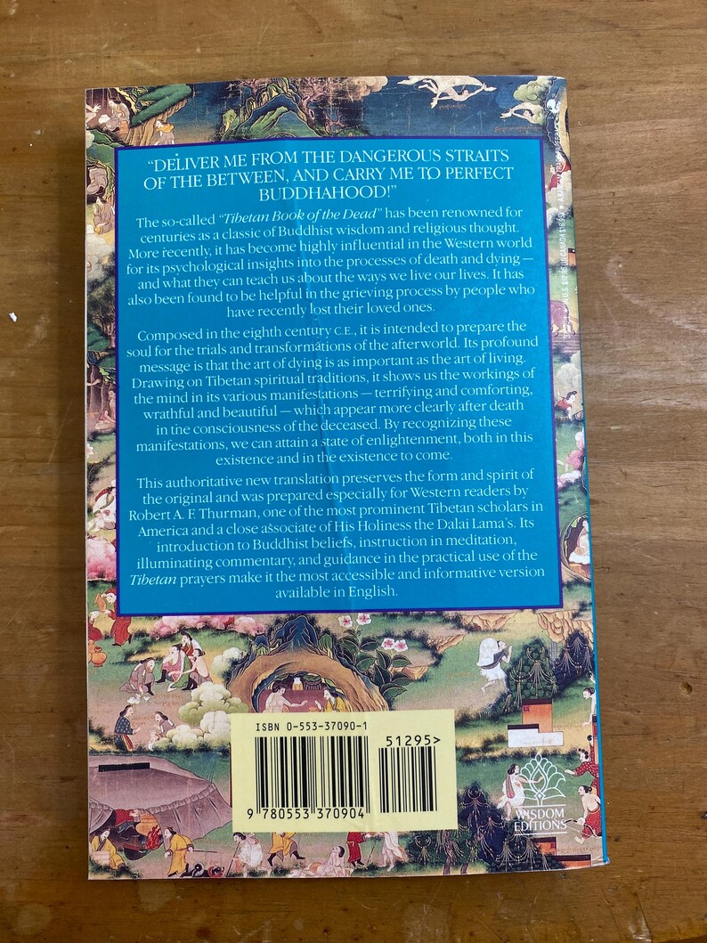 Puede incluir: La contraportada de un libro titulado "Tibetan Book of the Dead" con una ilustraci&oacute;n colorida de un paisaje con una tienda de campa&ntilde;a y personas. El libro se describe como un cl&aacute;sico de la sabidur&iacute;a budista y el pensamiento religioso. El n&uacute;mero ISBN es 0-553-37090-1.