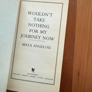 K&ouml;nnte beinhalten: Aufgeschlagene Buchseite mit dem Titel "WOULDN'T TAKE NOTHING FOR MY JOURNEY NOW" von Maya Angelou. Das Buch ist von Bantam Books herausgegeben, mit Standorten in New York, Toronto, London, Sydney und Auckland. Die Seite ist cremefarben.