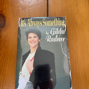 May include: A paperback book titled "It's Always Something" by Gilda Radner. The cover features a black and white photo of Gilda Radner wearing a black blazer and a white shirt.