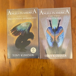 May include: Two books titled "Angels in America" by Tony Kushner. The first book, "Part One: Millennium Approaches," features a kneeling figure with angel wings. The second book, "Part Two: Perestroika," shows an angel with outstretched arms.