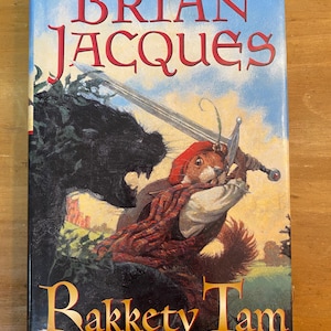Könnte beinhalten: Ein Buchcover mit einem roten Eichhörnchen mit einem Schwert, einem schwarzen Tier und dem Titel "Brian Jacques Rakkety Tam" in goldenen Buchstaben. Das Buch ist Teil der Redwall-Reihe.