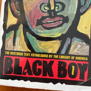 Op de afbeelding: Een boekomslag met een kleurrijk, abstract portret tegen een zwarte achtergrond. De titel "BLACK BOY" staat in vette, witte letters op een rode banner. De tekst "THE RESTORED TEXT ESTABLISHED BY THE LIBRARY OF AMERICA" staat boven de titel.