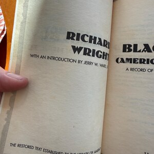 Op de afbeelding: Open boekpagina's met tekst. De linkerpagina leest "RICHARD WRIGHT" en "WITH AN INTRODUCTION BY JERRY W. WARD." De onderkant van de pagina luidt "THE RESTORED TEXT ESTABLISHED BY THE LIBRARY OF AMERICA."