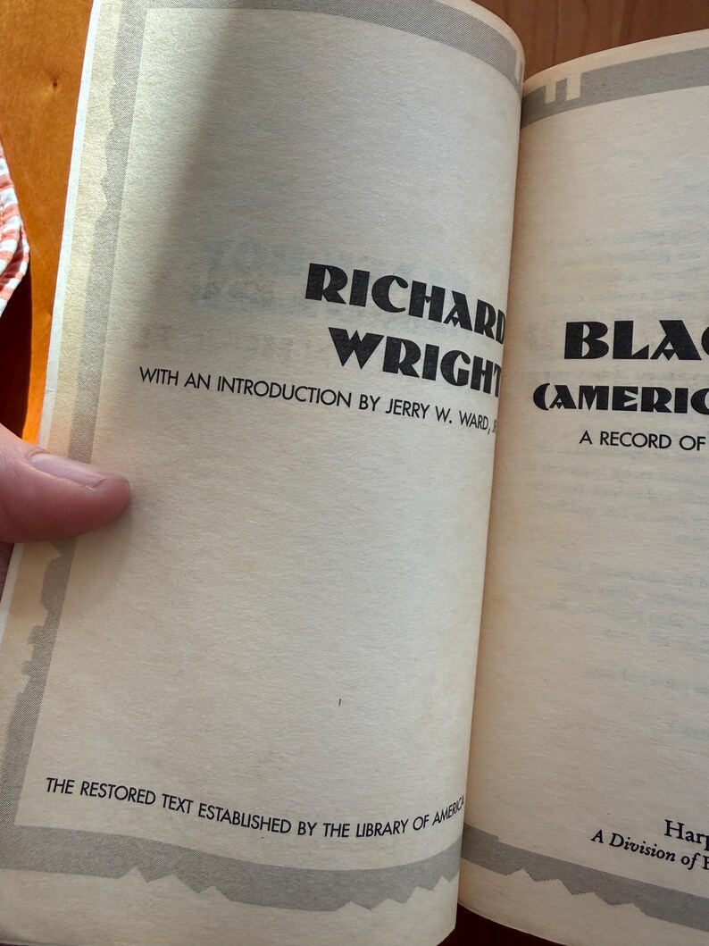 Op de afbeelding: Open boekpagina's met tekst. De linkerpagina leest "RICHARD WRIGHT" en "WITH AN INTRODUCTION BY JERRY W. WARD." De onderkant van de pagina luidt "THE RESTORED TEXT ESTABLISHED BY THE LIBRARY OF AMERICA."