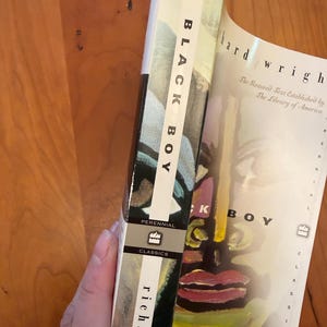 May include: A paperback book titled Black Boy by Richard Wright, published by Perennial Classics. The cover features a stylized, colorful painted face with bold brushstrokes in yellow, red, and black. The spine displays the title and author name.