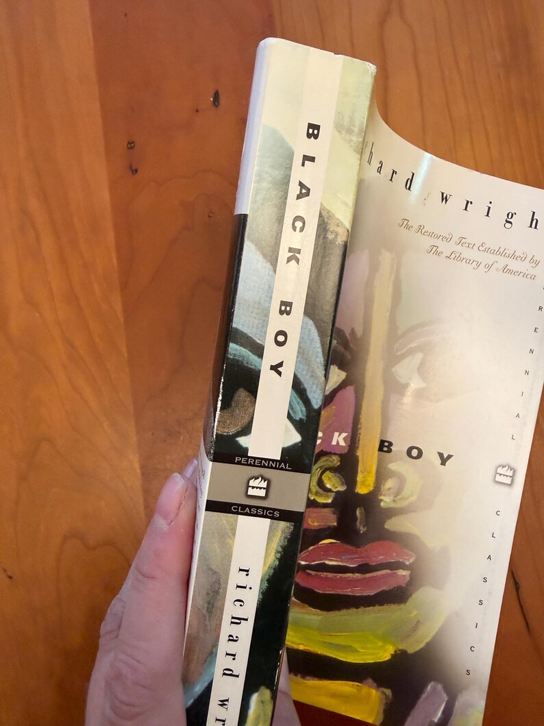 May include: A paperback book titled Black Boy by Richard Wright, published by Perennial Classics. The cover features a stylized, colorful painted face with bold brushstrokes in yellow, red, and black. The spine displays the title and author name.