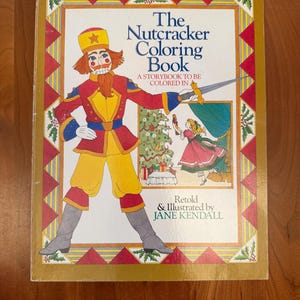 May include: A vintage "The Nutcracker Coloring Book" with a gold border. The cover features a colorful illustration of a nutcracker soldier and a girl. Text includes "A Storybook to be Colored In" and "Retold & Illustrated by JANE KENDALL."