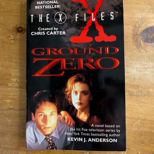 May include: A paperback book titled "THE X FILES GROUND ZERO" with the text "THE STUNNING NATIONAL BESTSELLER!" and "Created by CHRIS CARTER". The cover features two people and the text "A novel based on the hit Fox television series by New York Times bestselling author KEVIN J. ANDERSON".