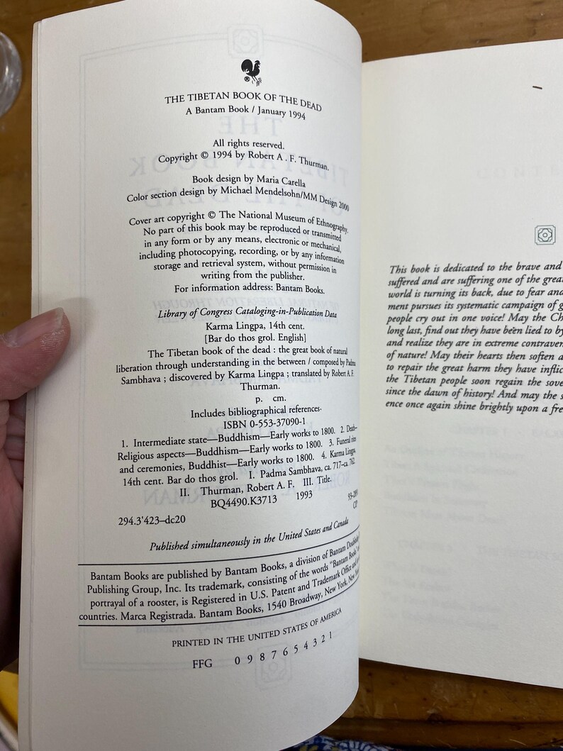 Puede incluir: Un libro blanco con una ilustraci&oacute;n de gallo negro en la portada. El t&iacute;tulo es "El Libro Tibetano de los Muertos" y el subt&iacute;tulo es "Un libro Bantam / Enero de 1994".