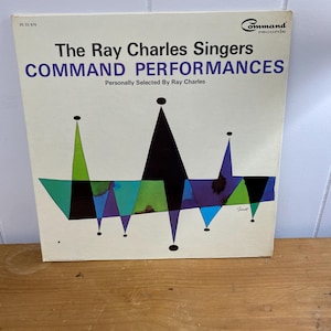 Puede incluir: Una portada de álbum de vinilo vintage con un diseño geométrico en negro, verde, azul y morado. El álbum se titula "The Ray Charles Singers Command Performances" y presenta el texto "Personally Selected By Ray Charles".