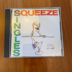 May include: A CD case with a white background and a colorful illustration of a person holding a glass. The text "SQUEEZE" is in large, colorful letters at the top of the case. The text "SINGLES" is in large, colorful letters down the left side of the case. The text "45's and under" is in smaller, black letters at the bottom right of the case.
