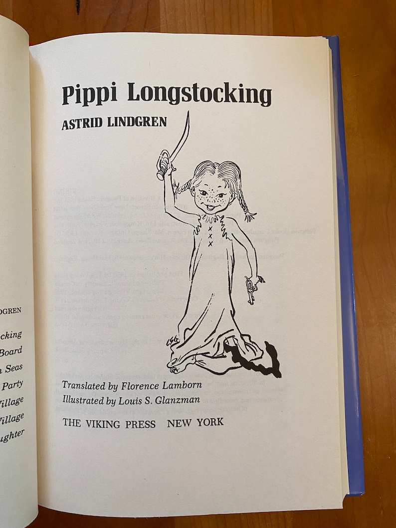 May include: Black and white illustration of Pippi Longstocking, a fictional character from the children's book series by Astrid Lindgren. Pippi is standing with her arms raised, holding a sword in one hand and a gun in the other. The book cover also includes the title "Pippi Longstocking" and the author's name, "Astrid Lindgren".