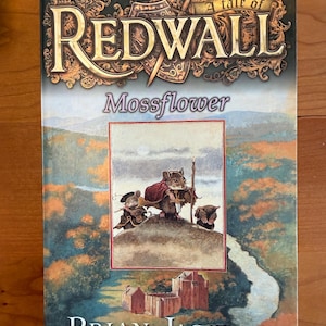 Könnte beinhalten: Ein Buch mit dem Titel "Redwall: Mossflower" von Brian Jacques. Das Cover zeigt eine Illustration von Mäusen in einer Landschaft mit einem Fluss und einem Schloss. Der Titel ist in einer dekorativen Schriftart gehalten, mit dem Text "Über 20 Millionen Exemplare verkauft!"