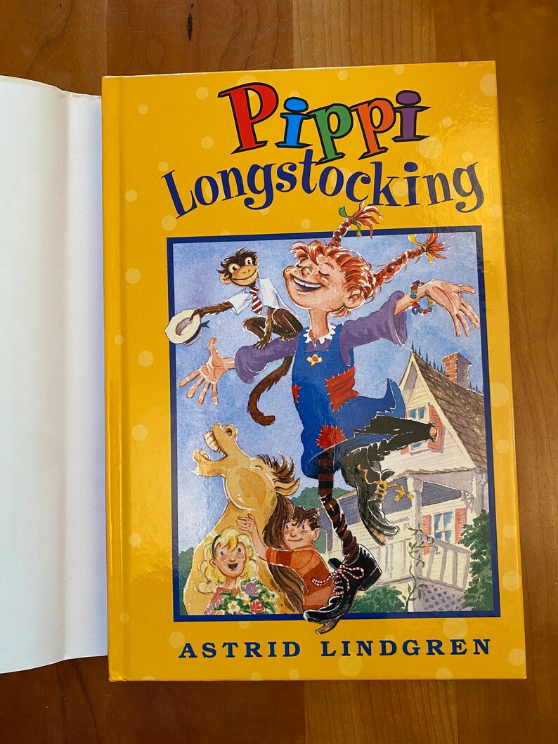 May include: A yellow book cover with a colorful illustration of Pippi Longstocking, a girl with red braids, jumping with a monkey on her shoulder. The book title is "Pippi Longstocking" and the author is "Astrid Lindgren".