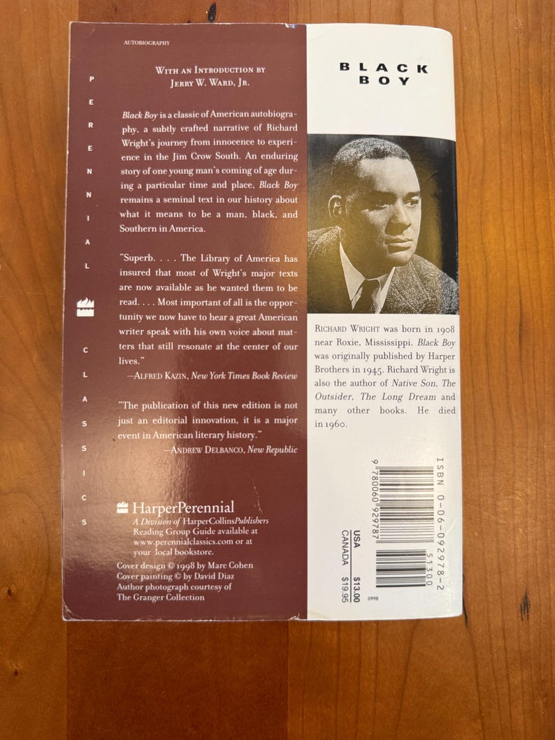 May include: The back cover of the book Black Boy by Richard Wright, featuring a black and white portrait of the author, a maroon background with white text, a summary of the autobiography, and a barcode with ISBN 0-06-092978-2 printed on it.