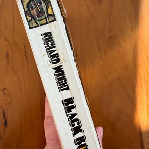 Op de afbeelding: Boekenrug met de titel "Black Boy" van Richard Wright. De omslag toont een portretillustratie met groene, blauwe en gele accenten. De rug is wit met zwarte tekst.