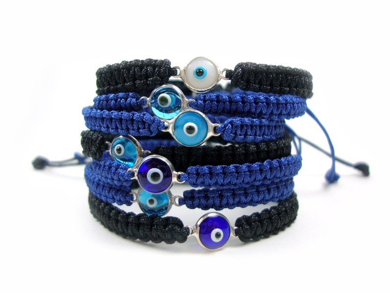 May include: A stack of blue and black braided bracelets with silver evil eye charms. The charms have blue and white centers.
