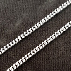 K&ouml;nnte beinhalten: Eine silberne Curb-Kette mit klassischem Design. Die Kette besteht aus miteinander verbundenen Metallgliedern, die ein robustes und stilvolles Schmuckst&uuml;ck bilden.