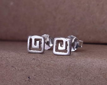 May include: A pair of silver earrings with a square design featuring a geometric pattern.
